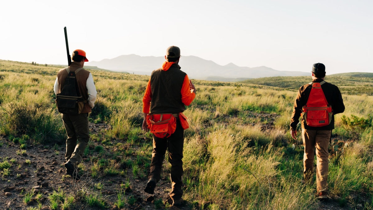 Duck Camp F26 — three hunters walking out across open country