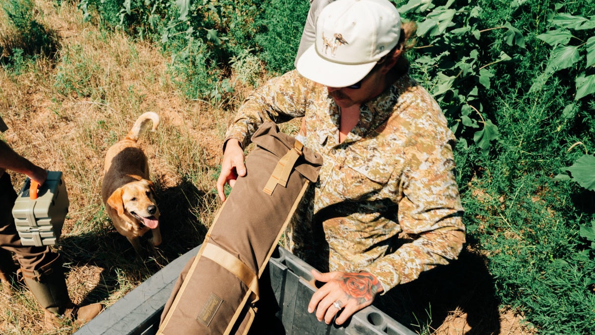 Duck Camp F26 — loading a gun case into a boat with a yellow lab alongside
