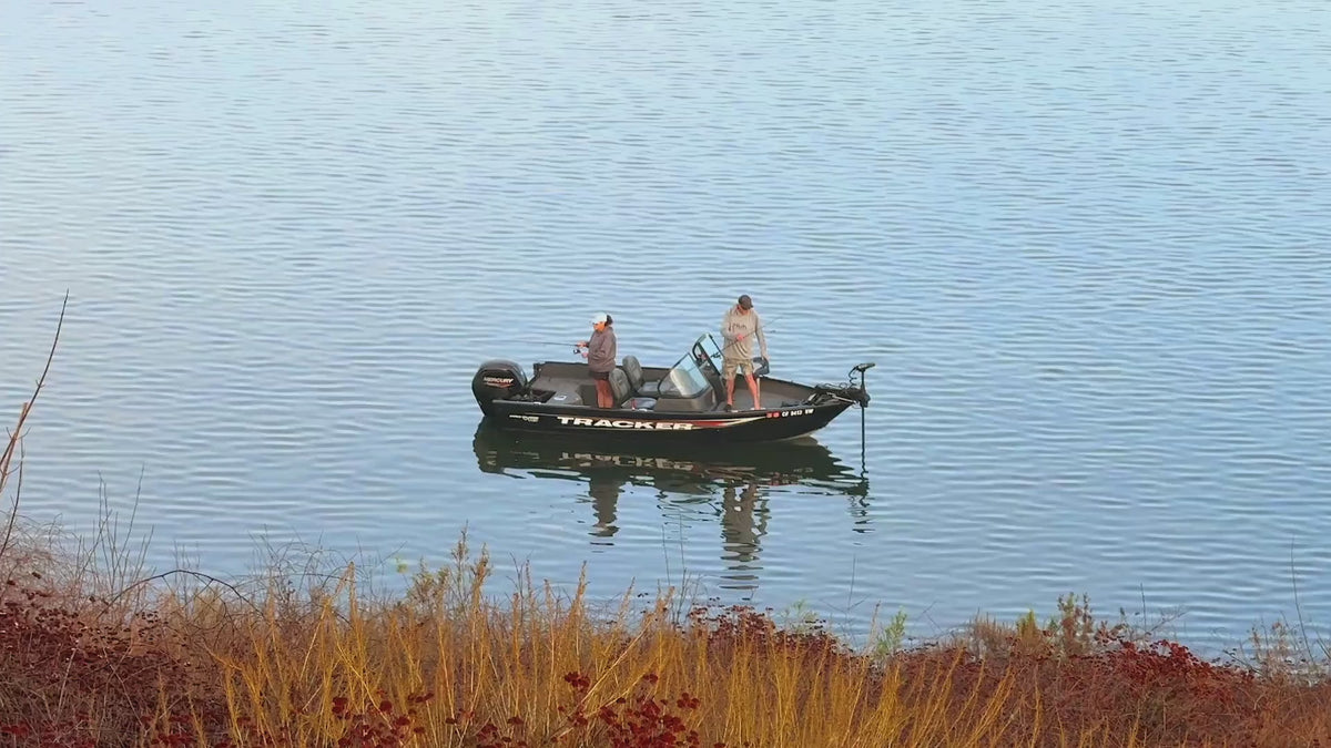 Load video: A fisherman works calm water from a small boat at first light.